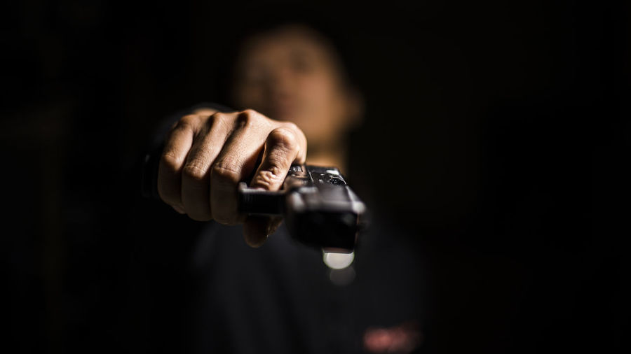 Close-up of man holding gun in darkroom