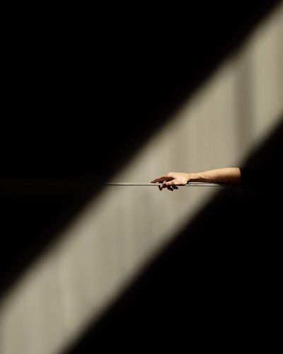 Cropped hand holding metal against wall with sunlight