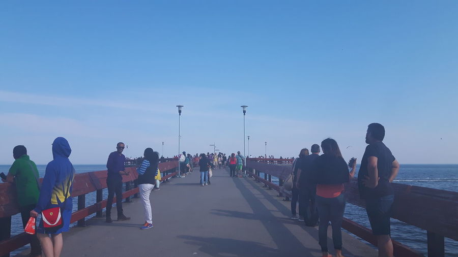 People on sea shore against clear sky