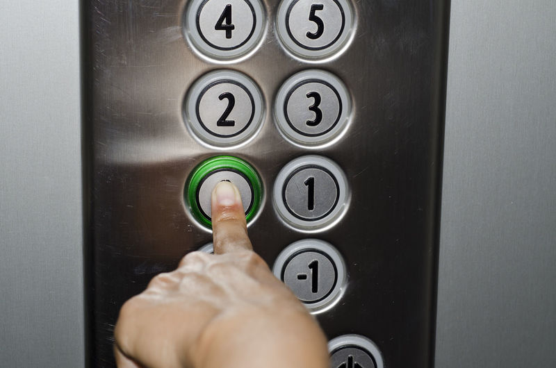 Cropped image of hand pressing button in elevator