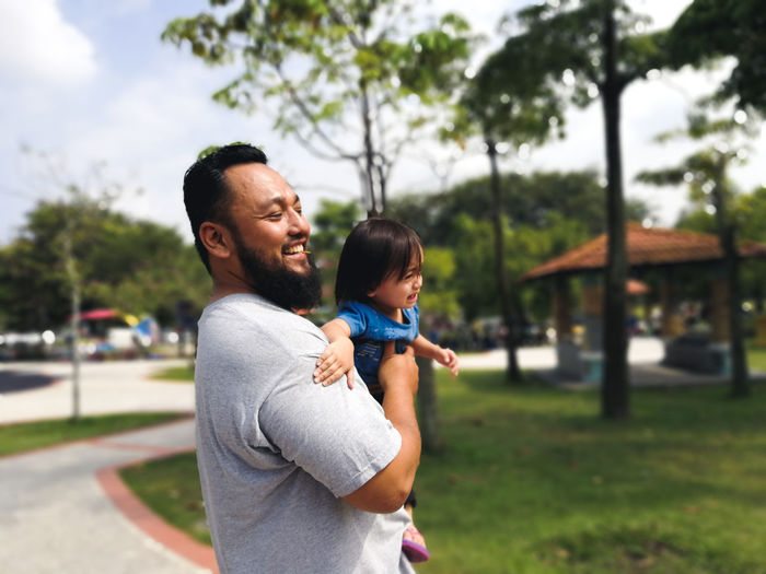 Smiling father carrying daughter in playground