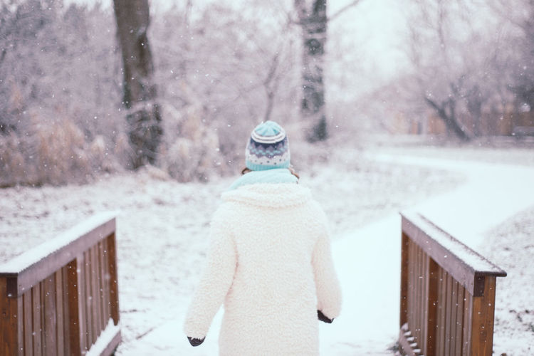Rear view of girl standing amidst railing during winter