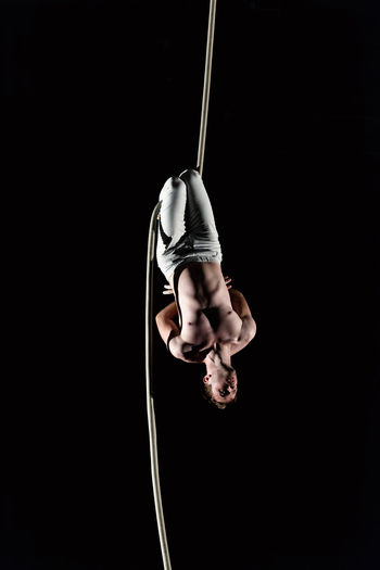 Young man doing gymnastics against black background