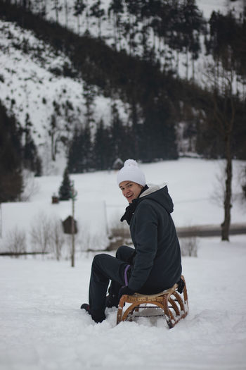 Man sitting on snow covered field