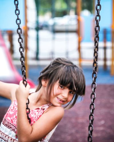 Portrait of woman sitting on swing at playground