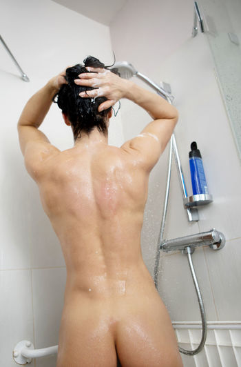 Rear view of naked woman bathing in bathroom