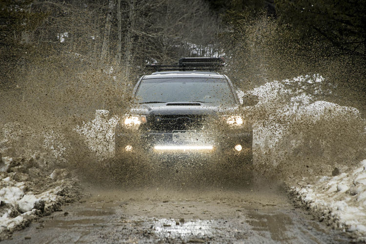 Off-road car splashing dirt on road during winter