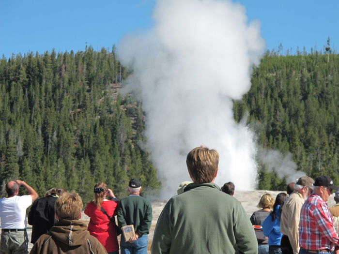 Rear view of people standing by steam emitting from field