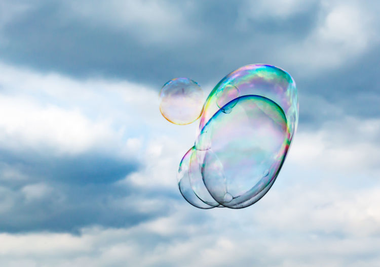 Low angle view of bubbles against cloudy sky