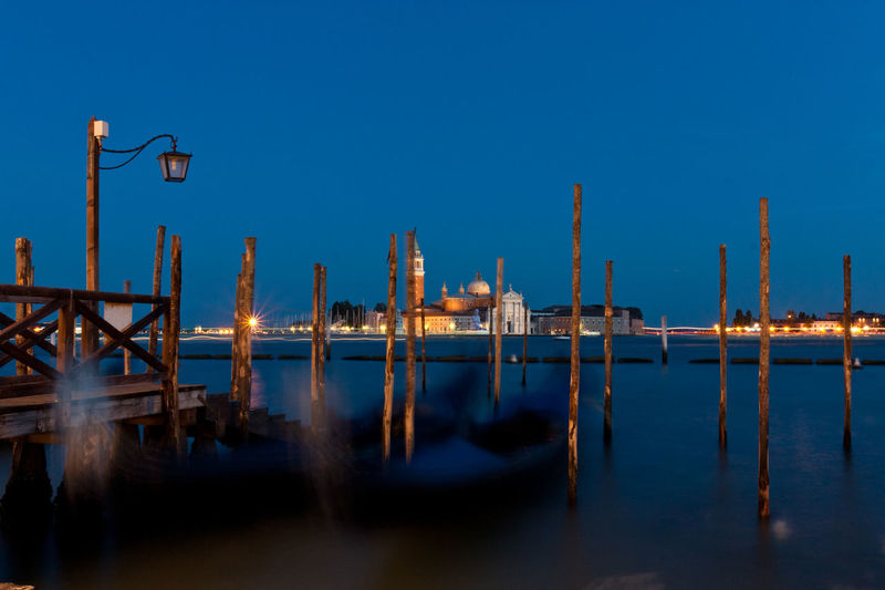Wooden posts in grand canal at night