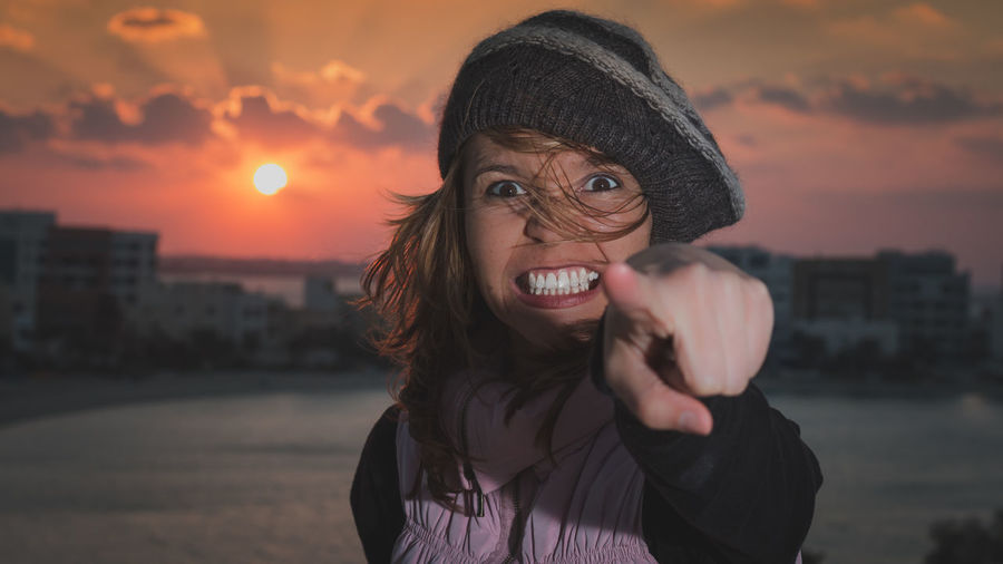 Portrait of angry woman standing against sky during sunset