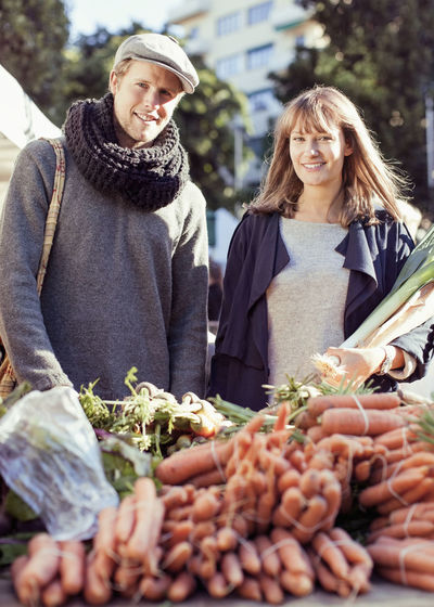 Portrait of couple buying vegetables at market