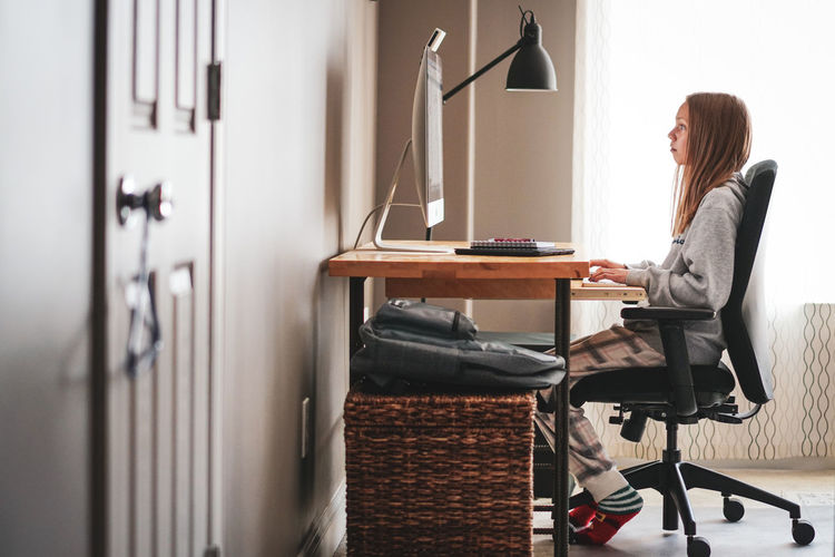 Side view of woman sitting on table in room