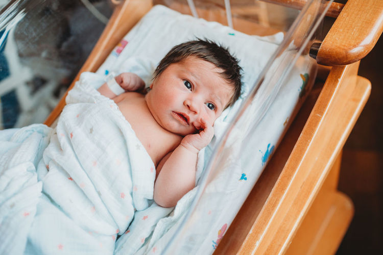 Awake newborn baby girl in hospital bed