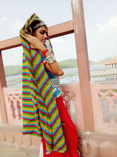Side view of woman in traditional clothing standing by railing