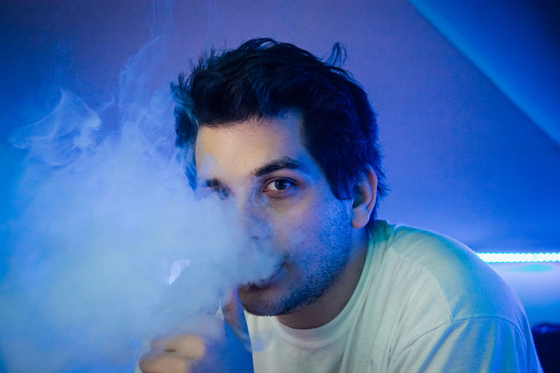 Close-up portrait of young man smoking in club