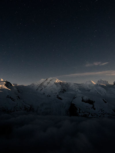 Scenic view of snowy covered mountains against sky at night
