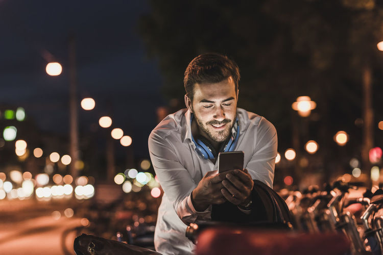 Young man in the city checking cell phone at night