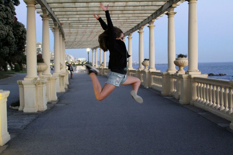 Girl jumping in colonnade by the sea
