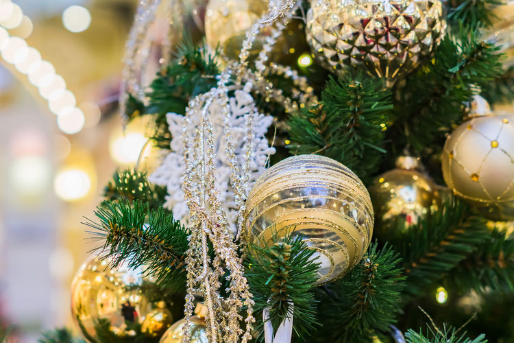 Close up of christmas tree decorated with gold and white balls and snowflake. new year background