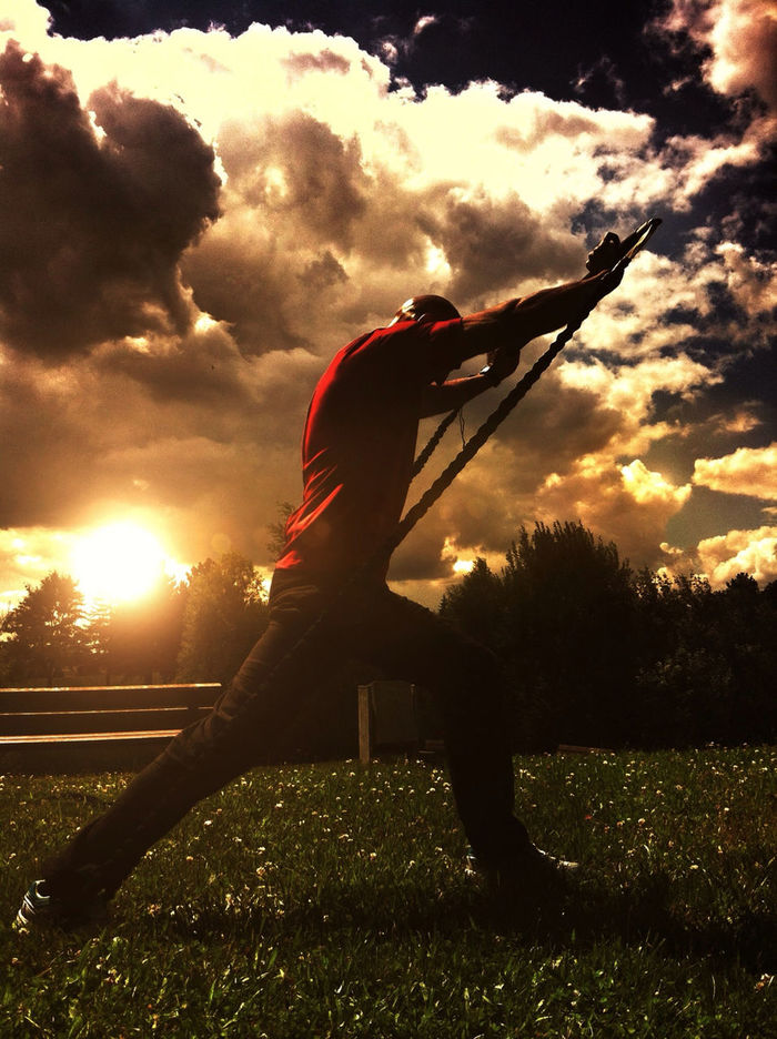 Side view of man doing exercises at sunset