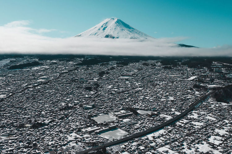 Aerial view of snowcapped mountain and cityscape against sky