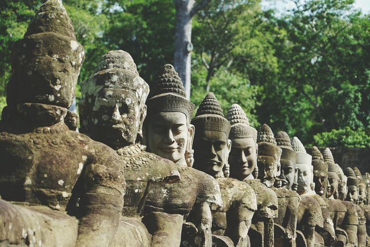 Close-up of buddha statues in row against trees