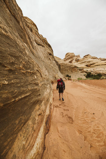 Hiker walks through sand in a dried arroyo in the maze canyonlands