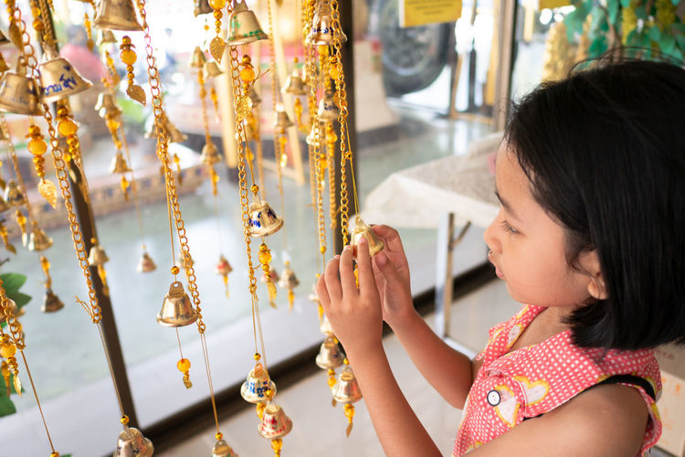 Girl looking at wind chime in home