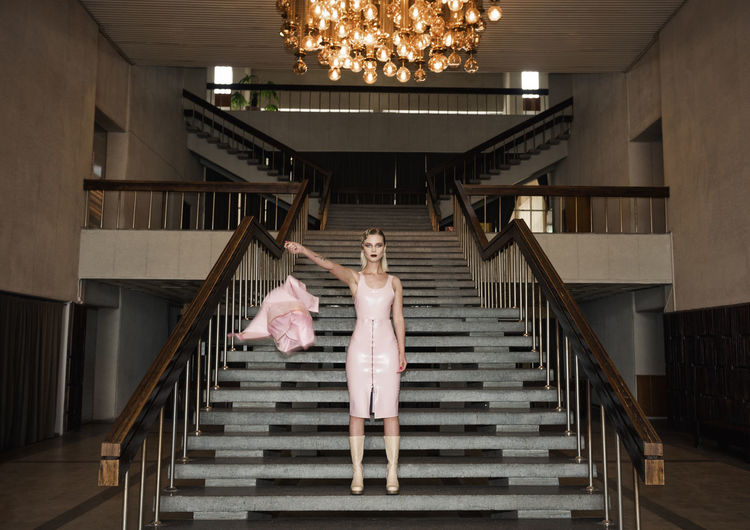 Full length of woman throwing jacket while standing on staircase