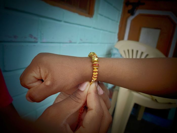 Cropped hand of girl tying rakhi to brother