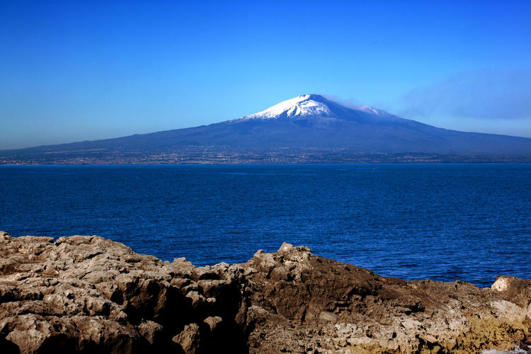 Cliff overlooking the mediterranean with the etna volcano in the background