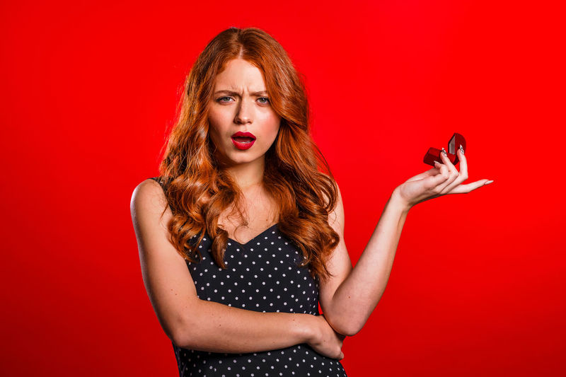 Portrait of young woman using phone against red background