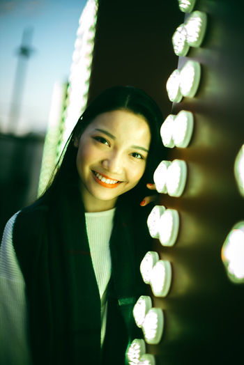 Close-up portrait of smiling young woman against blurred background