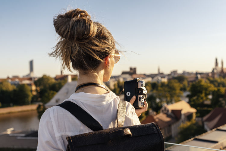 Rear view of woman photographing cityscape