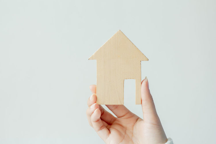 Woman holding model home against gray background