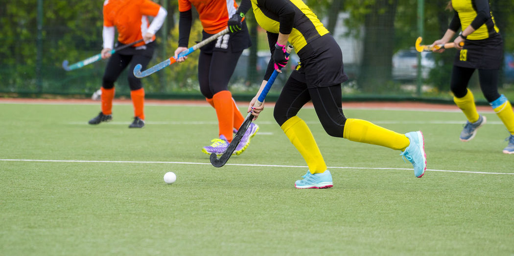 Low section of people playing hockey on field