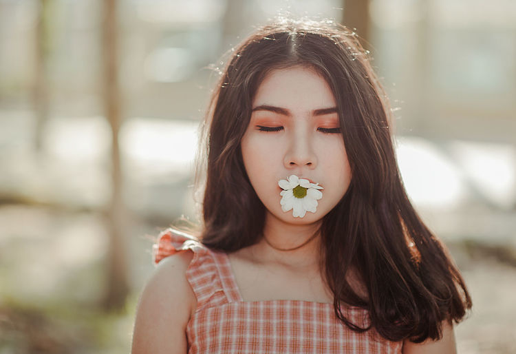 Close-up of beautiful woman holding flower in mouth