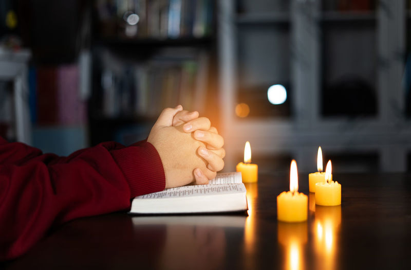 Cropped hand of woman holding illuminated candle