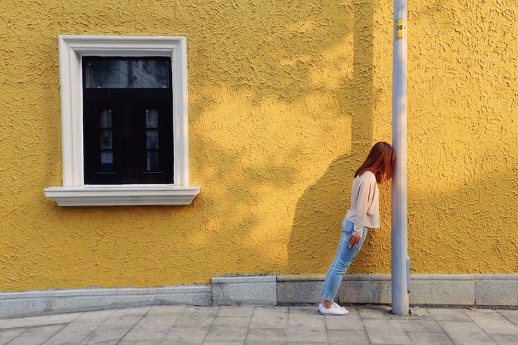 Woman standing against yellow building