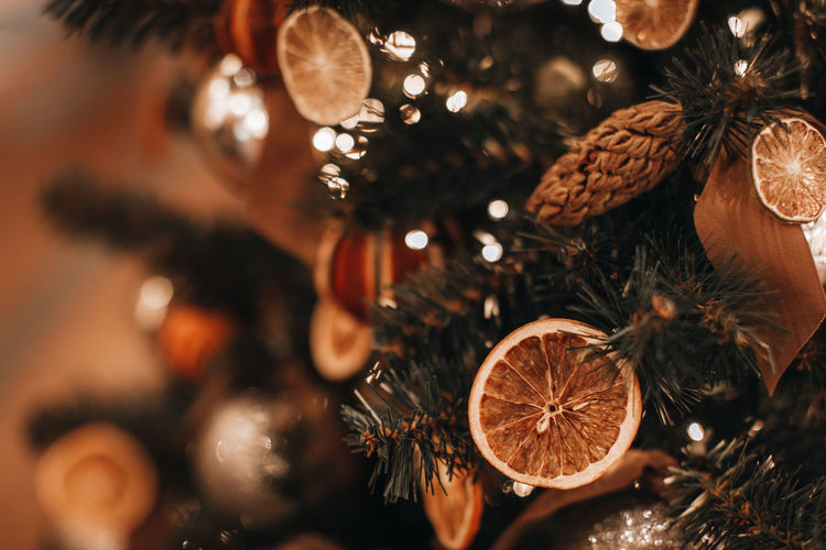 Creative christmas tree decorated with dry oranges and pine cones. magic golden bokeh lights 
