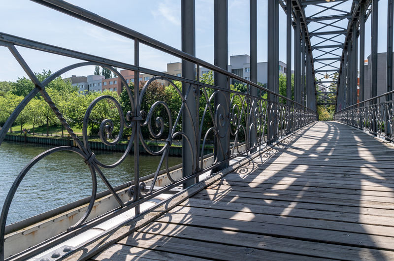Footbridge over river in city against sky