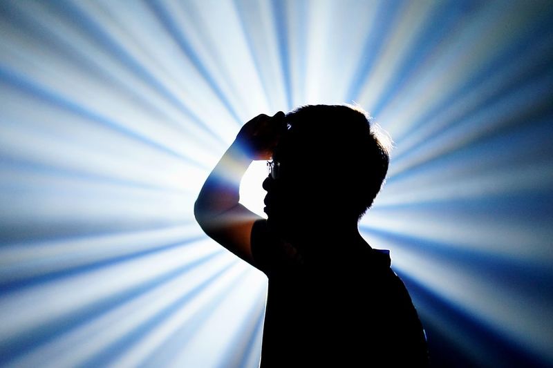 Young man gesturing against light beams