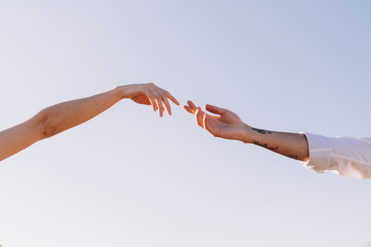 Low angle view of hands against clear sky