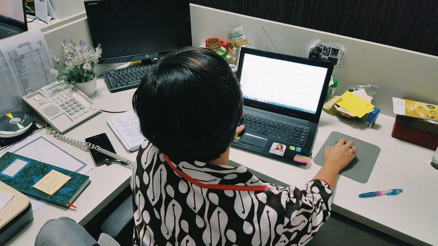 Rear view of businesswoman working with laptop at office