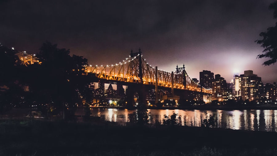Low angle view of illuminated queensboro bridge over east river at night