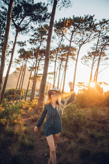 Woman standing against trees during sunset