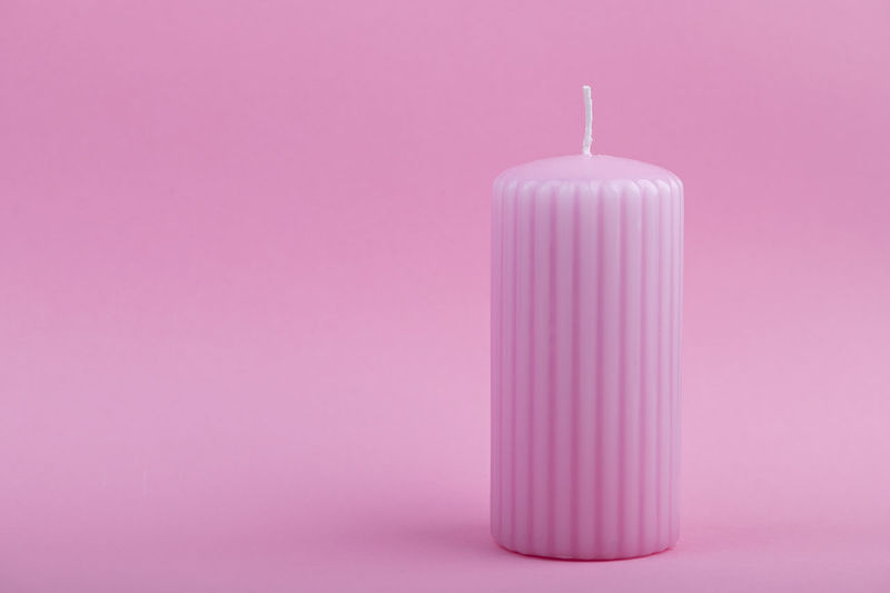 Close-up of candle on pink background