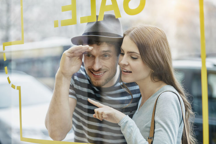 Young couple looking through window of a coffee shop