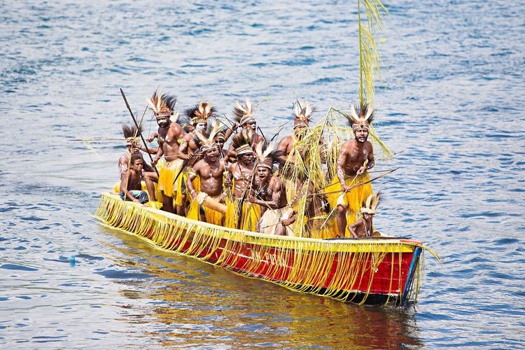 Group of people in traditional outfit on canoe